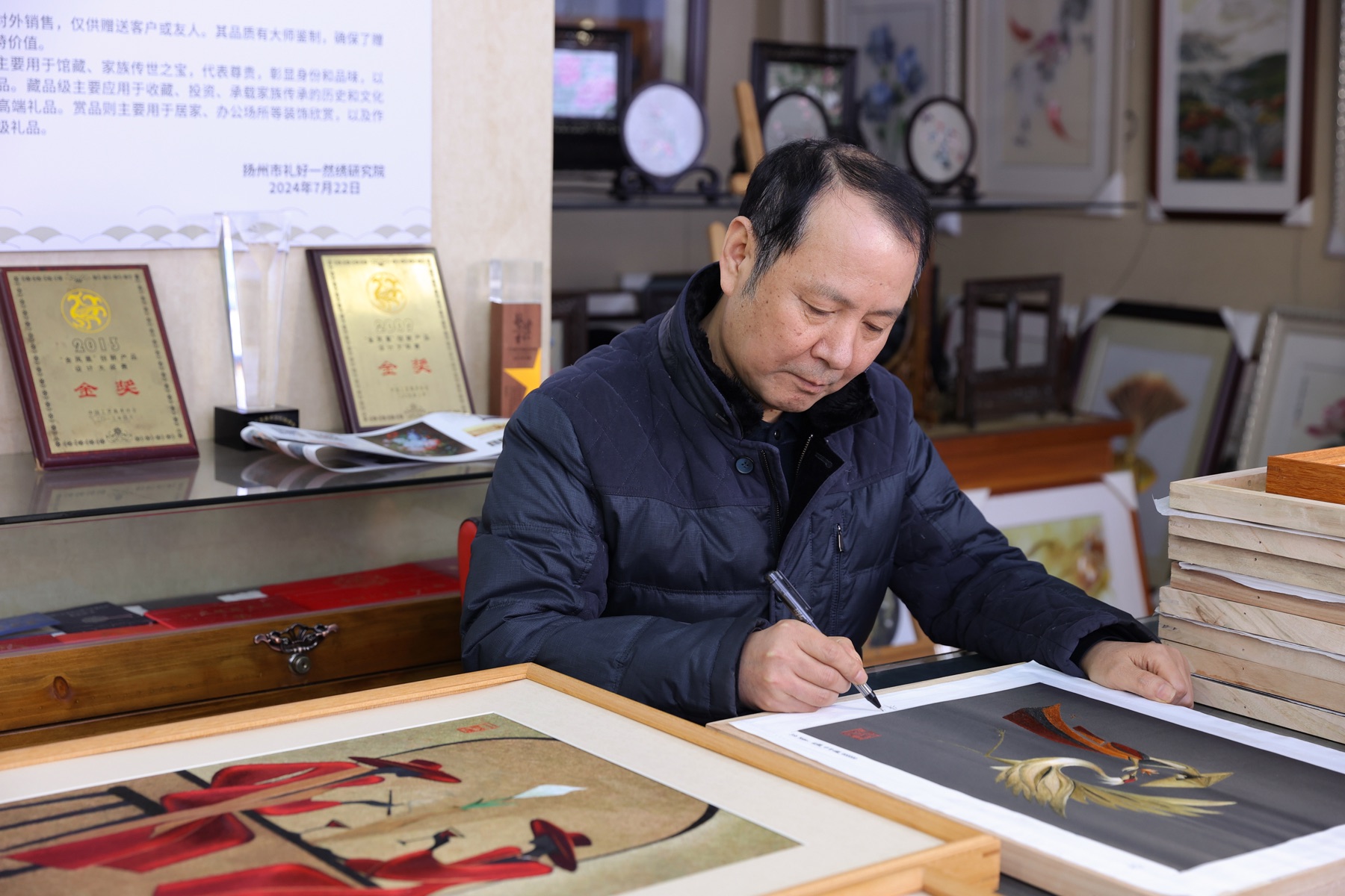 Master Zhu Juncheng signing finished embroidery in his studio.